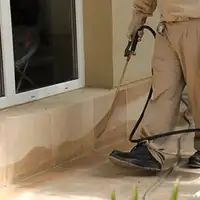 General pest control technician spraying exterior perimeter around a home in Springfield, MO