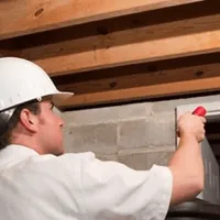 Termite inspection technician checking a basement wall and framing for termite activity in Springfield, MO
